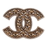 This brooch is in?gold tone metal with clear crystals on?a quilted CC logo.