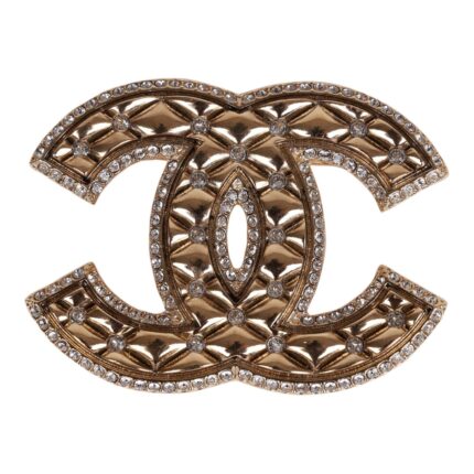 This brooch is in?gold tone metal with clear crystals on?a quilted CC logo.