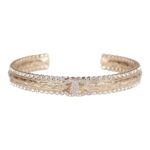 This cuff bracelet is in?gold tone metal with a clear crystal CC logo.