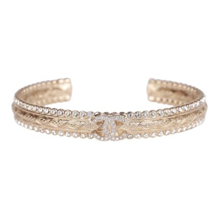This cuff bracelet is in?gold tone metal with a clear crystal CC logo.