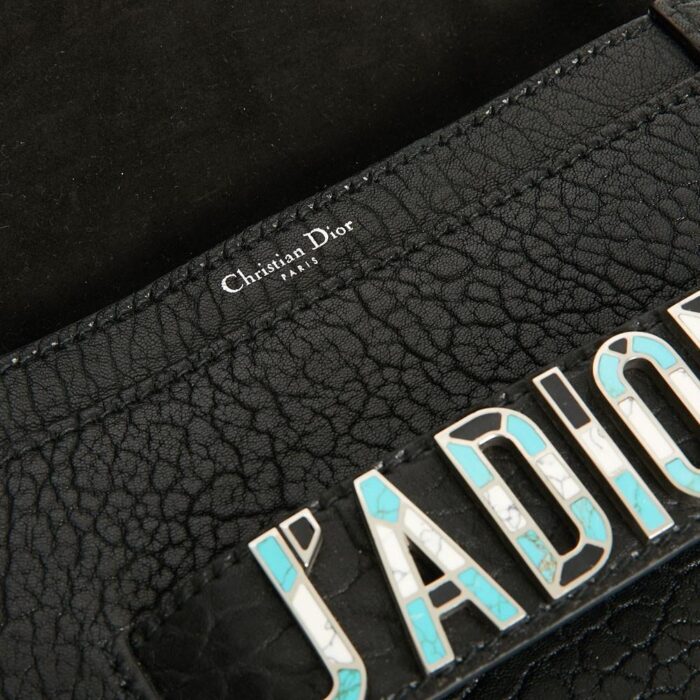with several pockets including one with a flap. Closing by a magnetic flap. It is signed "Christian Dior Paris". The metal plate on the front of the bag is the signature of the collection. It has never been used. It's made in Italy