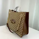 this spacious tote features a large double-handled silhouette and a chain shoulder strap for a touch of contemporary flair. Its organizational interior and magnetic snap closure add functionality to its stylish design.The Gucci 1955 Horsebit Large Tote Bag pays homage to the original bag that inspired the line over six decades ago