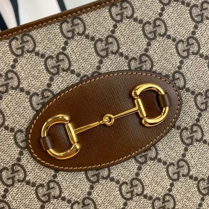a sustainable material. It is accentuated with brown leather trim and showcases gold-toned hardware