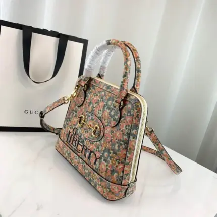 available in a size of 9.8 W x 9.5 H x 3.5 D (25 x 24 x 9 cm). This exquisite bag features a delicate light pink and light blue floral print by Liberty London on ivory leather