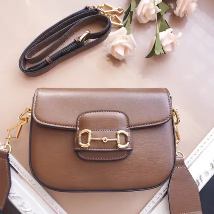 The Gucci Horsebit 1955 Mini Bag in Brown/Black/White is a stunning accessory that adds a touch of sophistication to any outfit. This petite version of the vintage-inspired line is designed with versatility in mind. It comes with two detachable shoulder straps