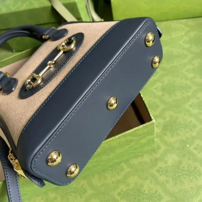 the bag showcases gold-toned hardware with the distinctive double ring and bar Horsebit motif. The canvas top handle bag is accentuated with navy buffed leather trim