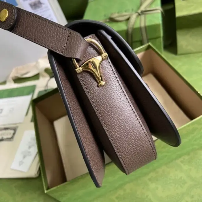 this bag showcases the signature Gucci pattern. It is accentuated with brown leather trim and complemented by gold-toned hardware for a touch of luxury. The microfiber lining with a suede-like finish adds to its elegance.The bag comes with a small pouch containing two additional button covers. These covers can be used to conceal the exposed studs when the shoulder strap is extended
