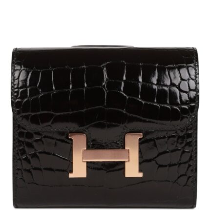 This Constance compact wallet is in black shiny alligator with rose gold hardware and has tonal stitching