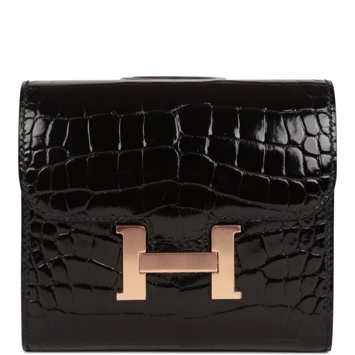 This Constance compact wallet is in black shiny alligator with rose gold hardware and has tonal stitching