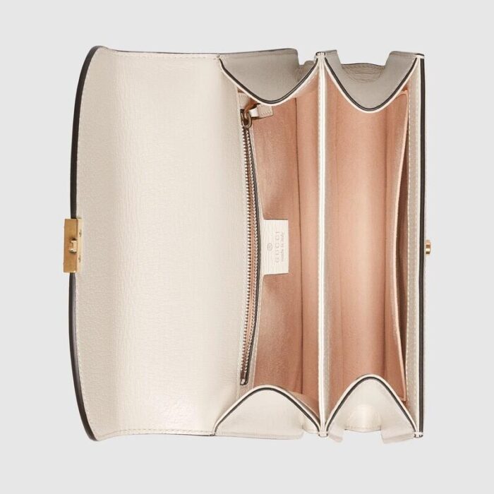with retro-inspired details and classic brand elements. This handbag is crafted in beige and ebony GG Supreme canvas with classic white leather piping and a detachable shoulder strap. The red and blue striped web intarsia details pay homage to the brand's equestrian origins and complement the overall look.