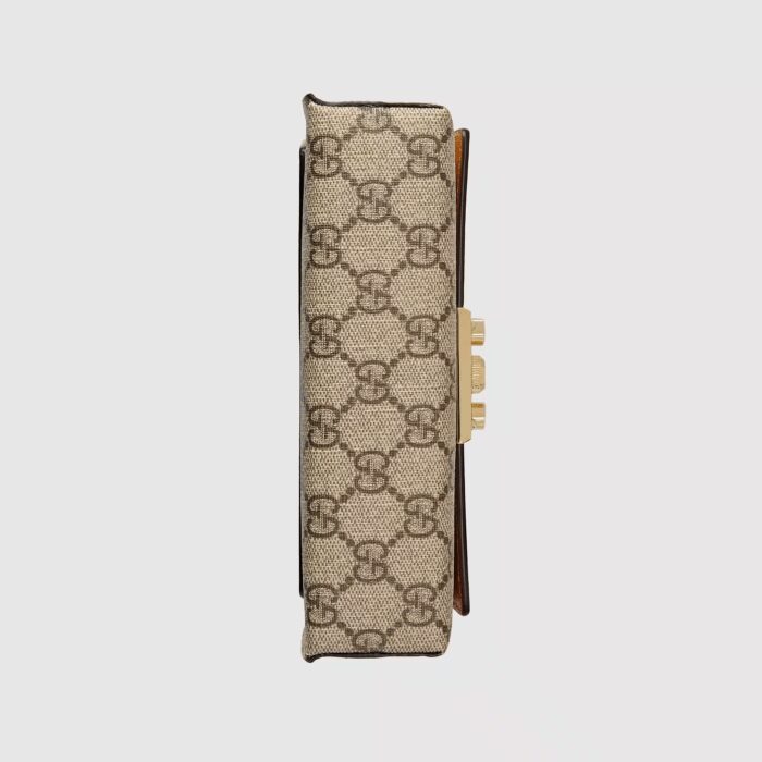 the Padlock is defined by its signature lock and key closure. The accessory is crafted from beige and ebony GG Supreme canvas with a white leather top. Adding a pop of color